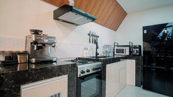 A modern kitchen with a stove, oven, and coffee machine.