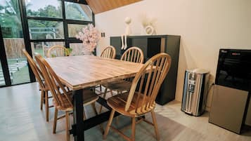 A dining area with a wooden table and chairs, a black cabinet, and a trash can.