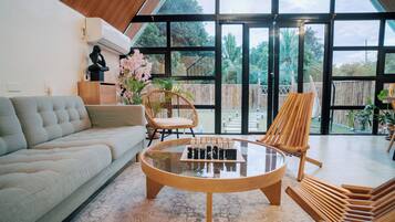 A modern living room with a sofa, a glass coffee table, and two wooden chairs.