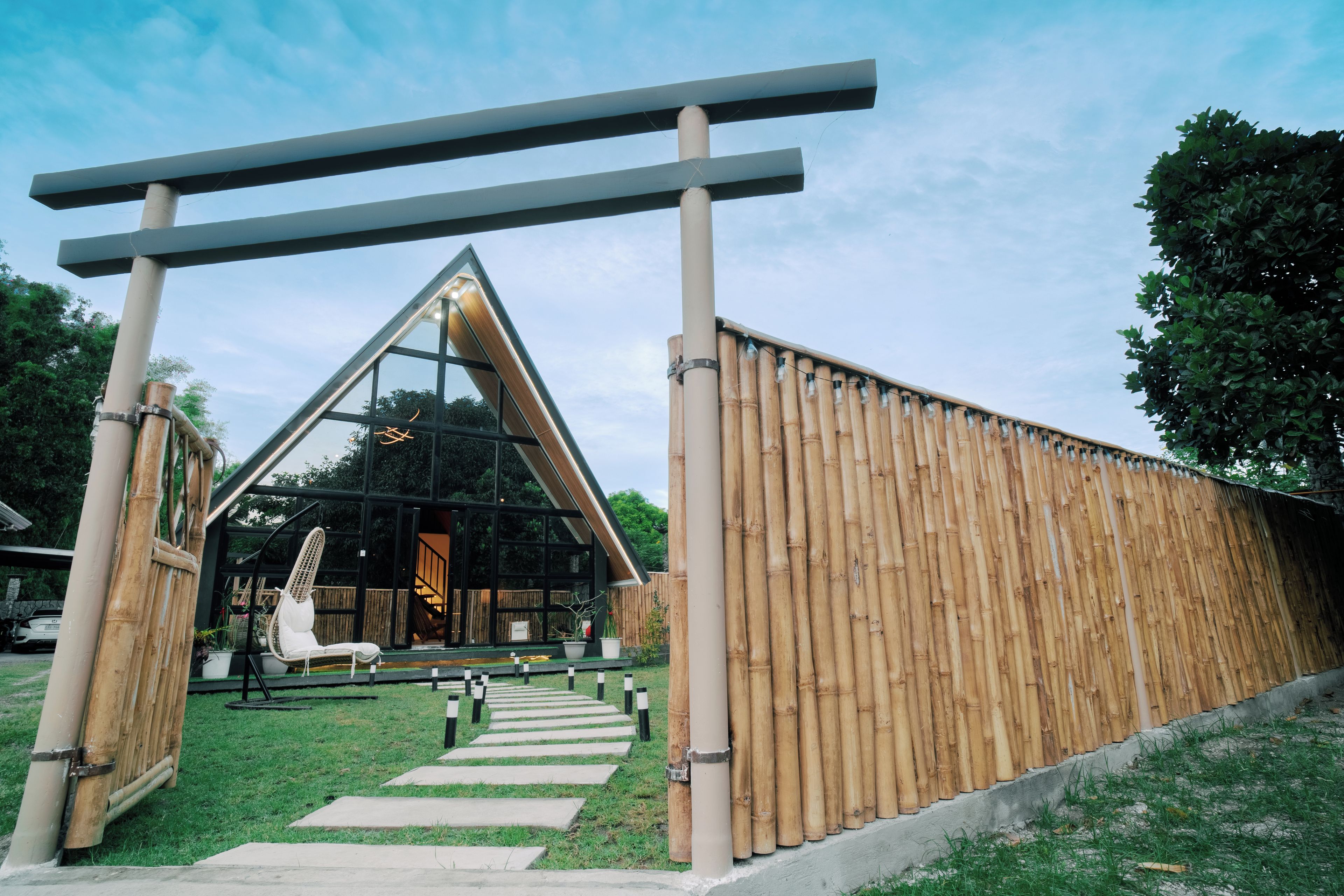 Un bâtiment moderne avec une façade en verre, une clôture en bois et un ciel dégagé.