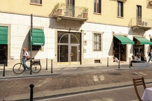 Un carrer amb un edifici que té una tenda verda, una bicicleta aparcada al davant i una zona per a vianants.