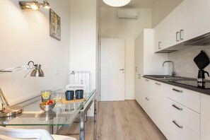 A modern kitchen with a glass dining table, stainless steel appliances, and a white cabinet. - Apartment in Milan with 1 bedrooms sleeps 2 (Milan)