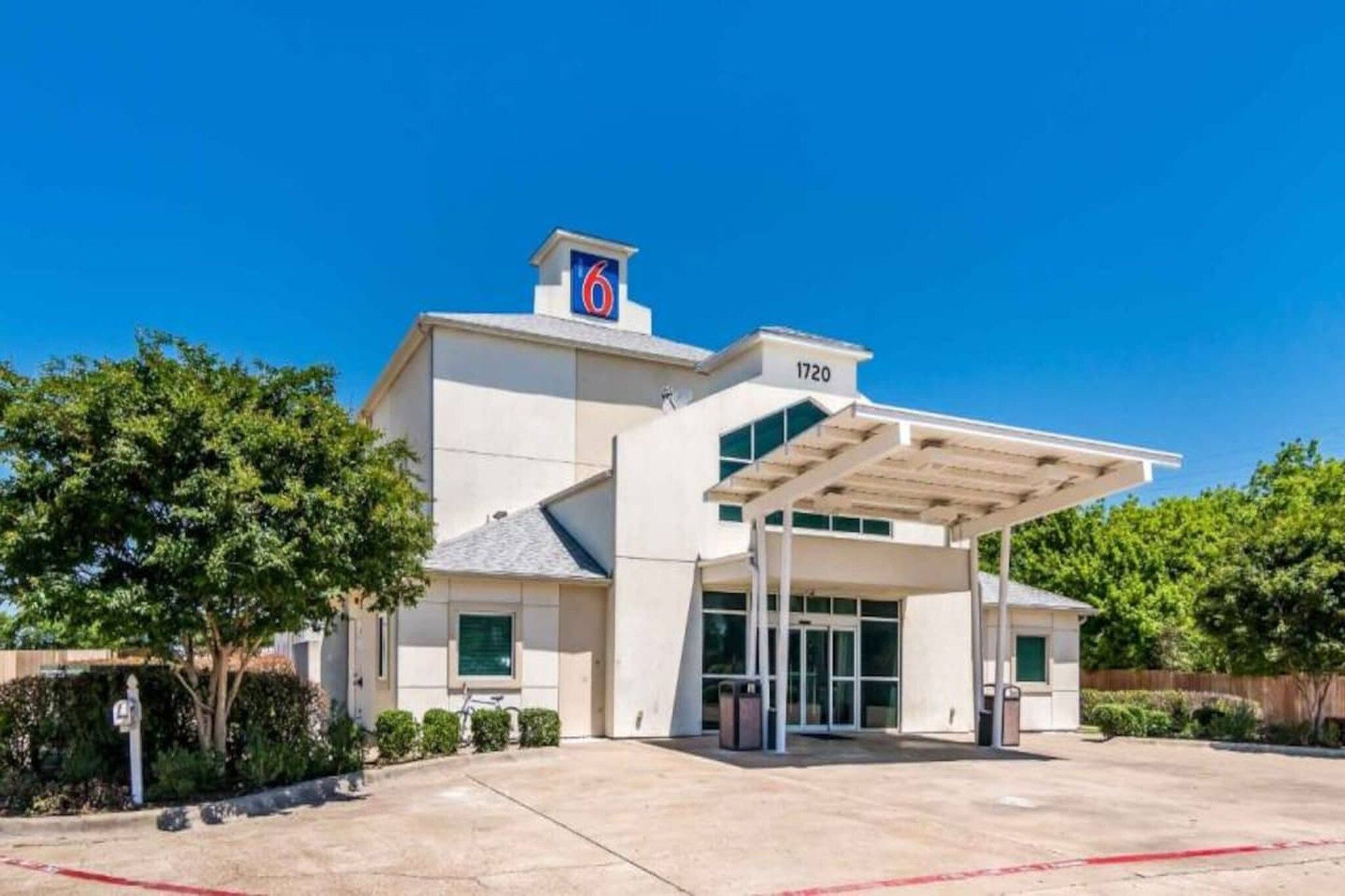 A modern hotel with a covered entrance, a prominent number sign, and a clear sky.