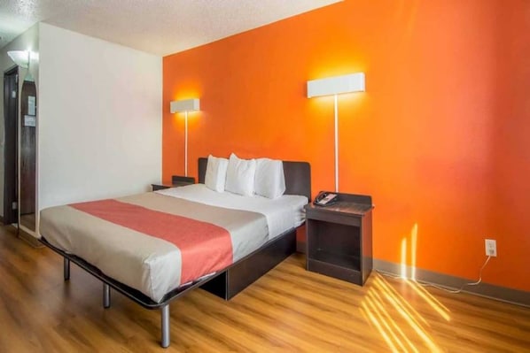 Una camera d'albergo con un letto, comodini e una lampada a parete.