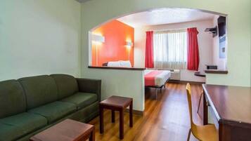 A compact living space with a sofa, a small table, a dining area with a chair, and a kitchenette.