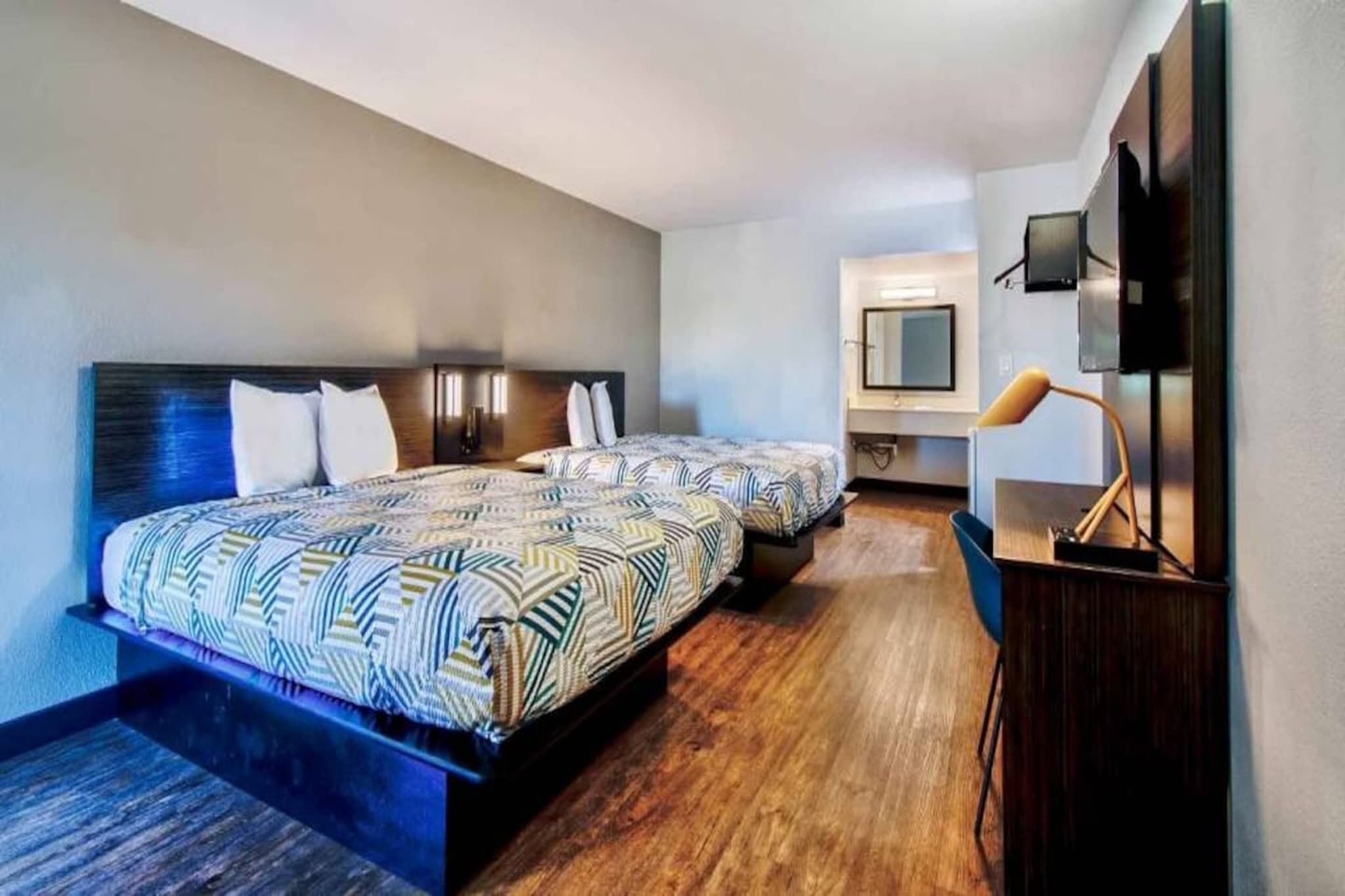 Een hotelkamer met twee bedden, een televisie en een bureau met een lamp.