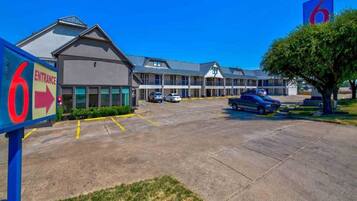A motel with a clear entrance sign, multiple parking spaces, and a large building with a flat roof.