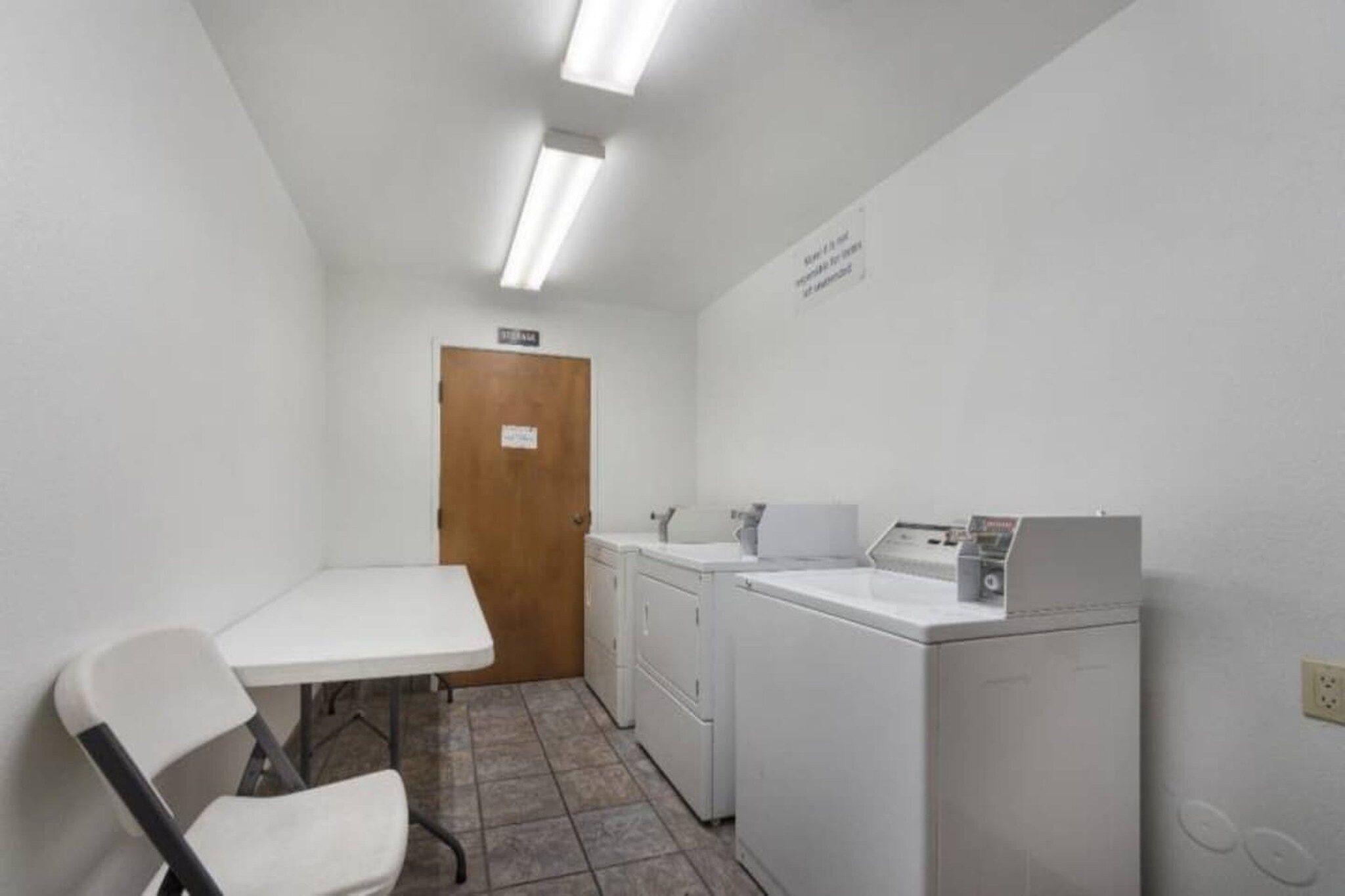 A small laundry room with a table, chairs, a washing machine, and a dryer.