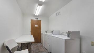 A small laundry room with a table, chairs, a washing machine, and a dryer.