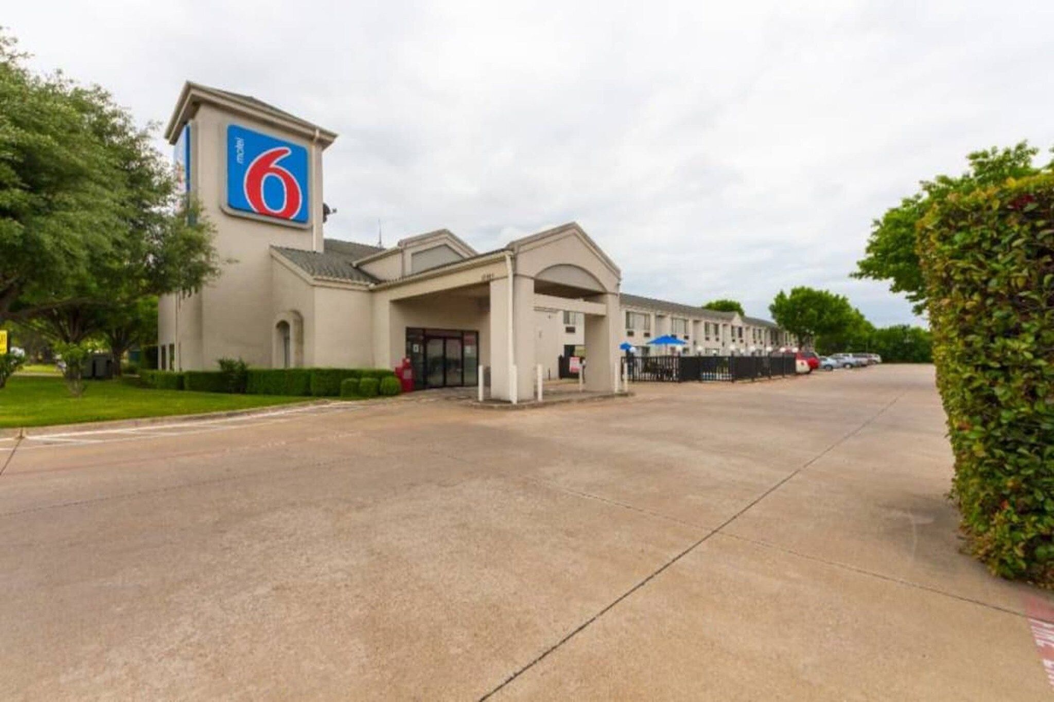 A 6-story motel with a large entrance and a parking lot.