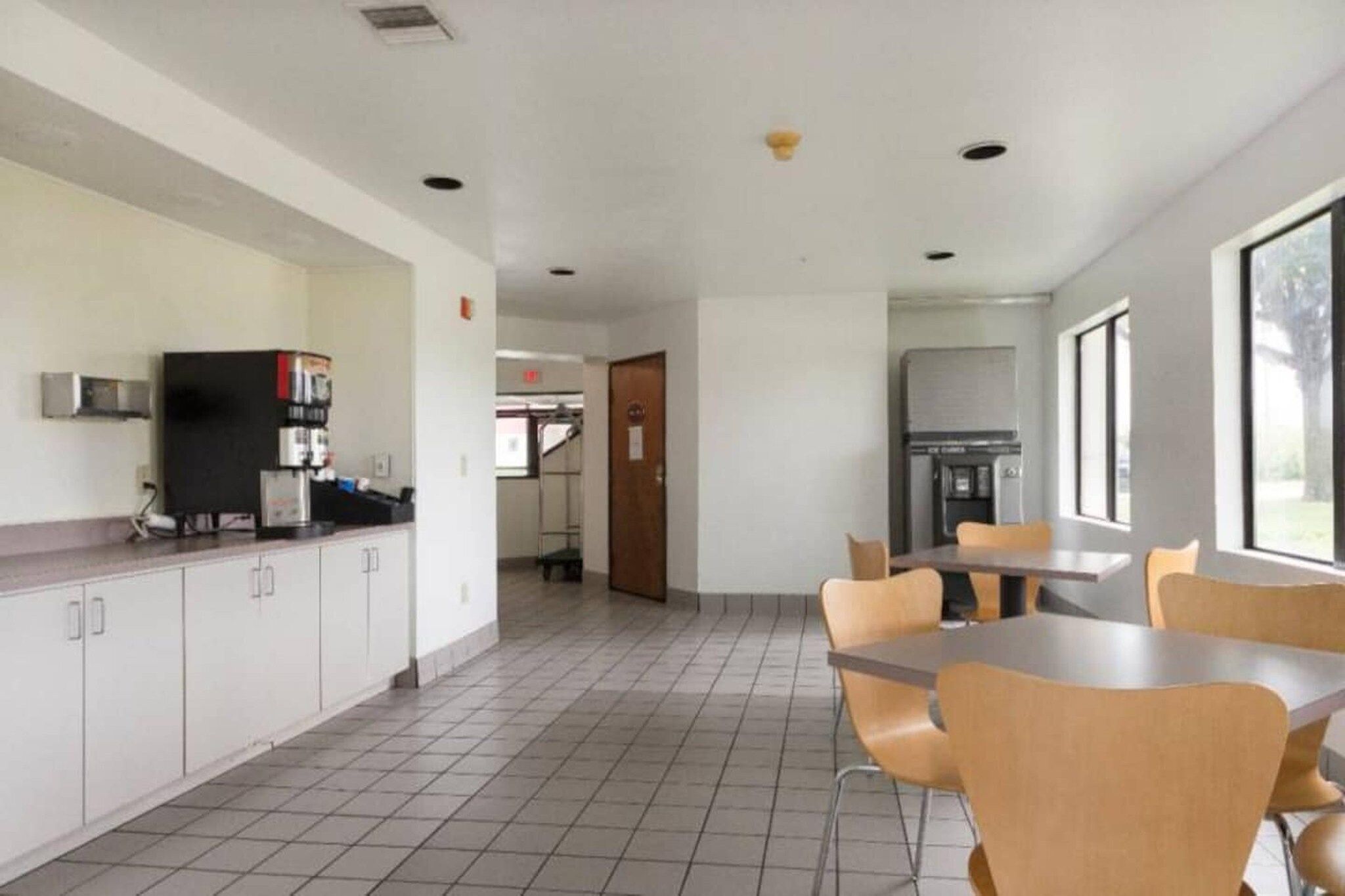 A spacious indoor area with a kitchen counter, a refrigerator, and a dining table with chairs.