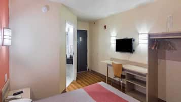 A hotel room with a bed, a desk, a chair, a television, and a wardrobe.