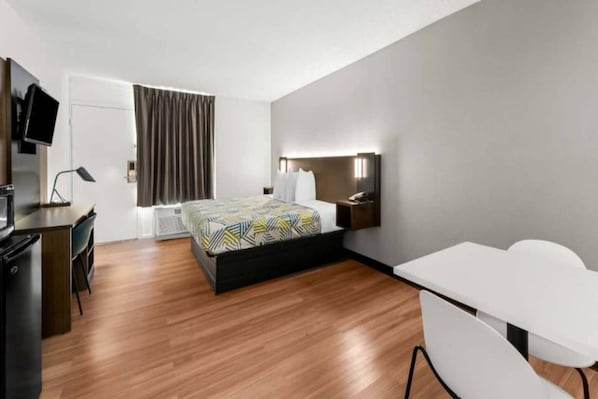 A hotel room with a bed, desk, chair, and a TV. - 1 King Bed | Non-Smoking, Micfridge (Port Lavaca)