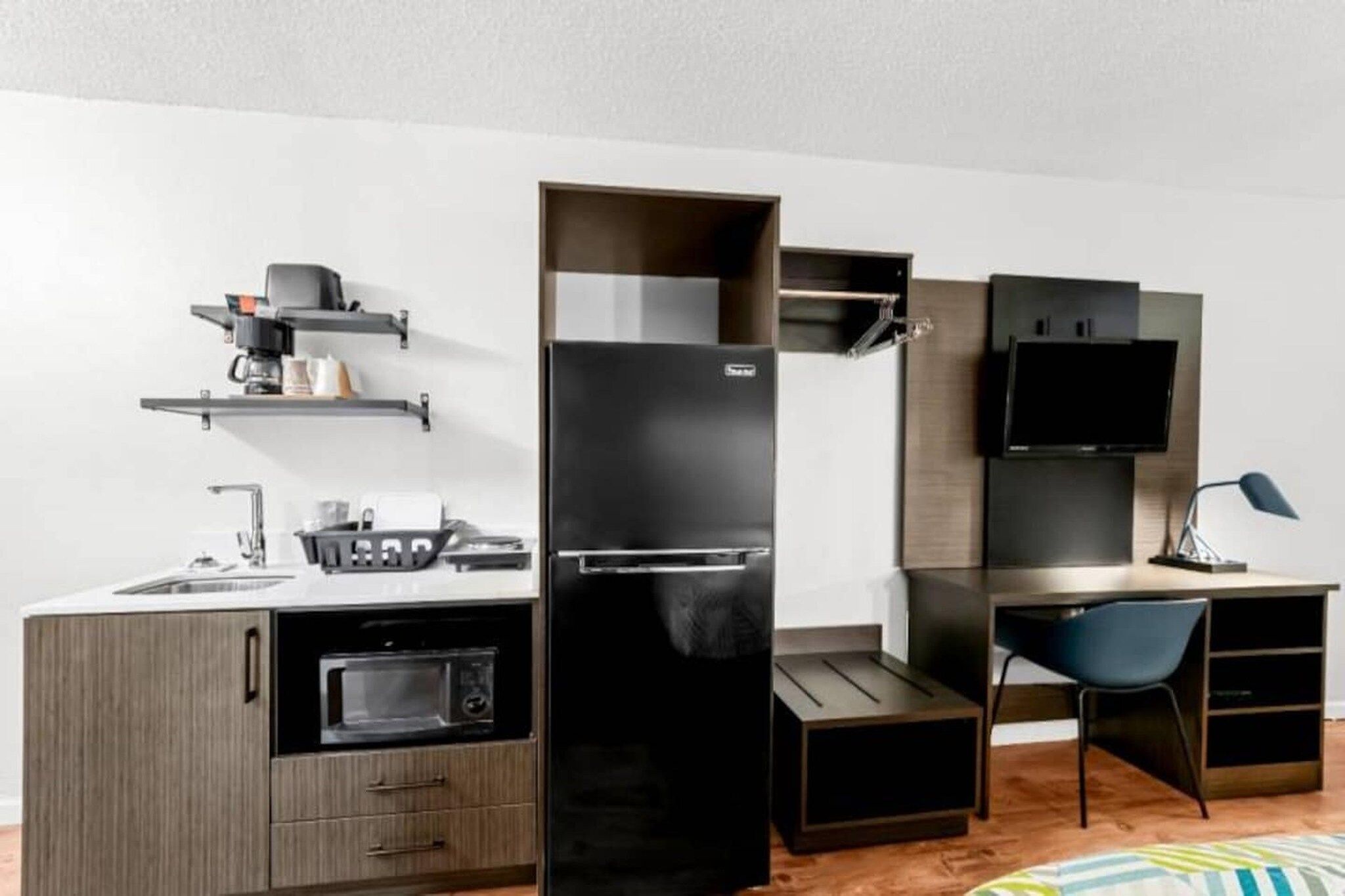 A compact kitchenette with a microwave, refrigerator, and a small sink.