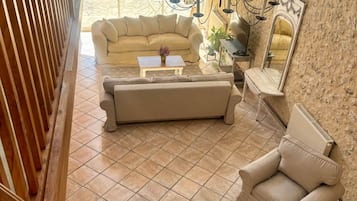 A spacious living area with a large sofa, a smaller sofa, and a chair, a coffee table, and a mirror on the wall.