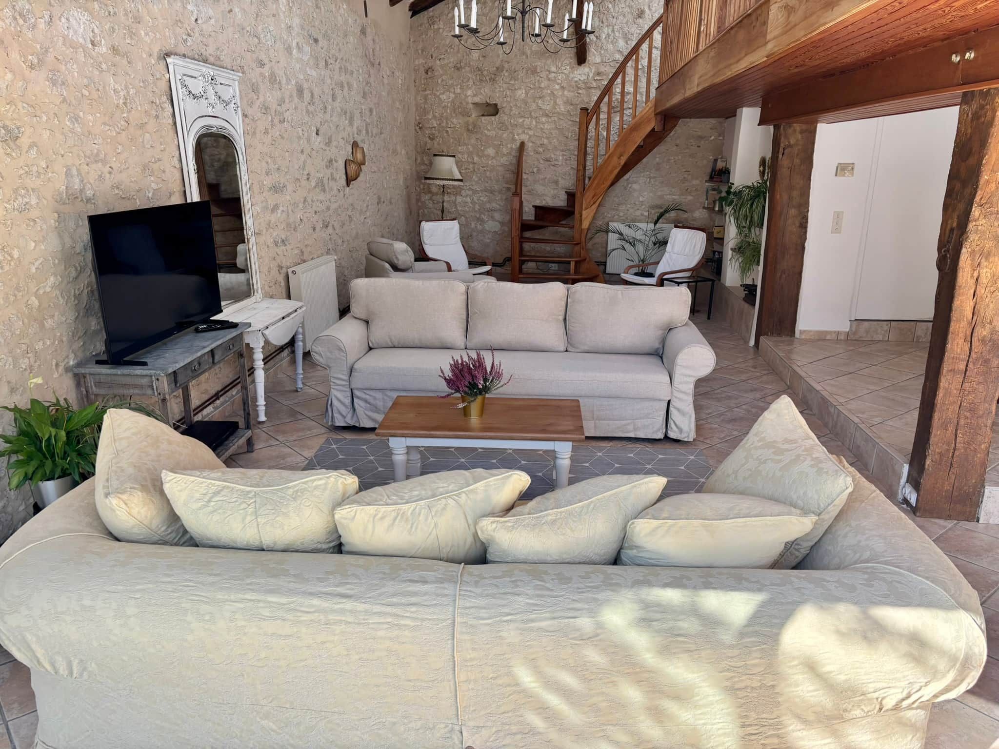 A living room with a sofa, a coffee table, a TV, and a staircase leading to another level.