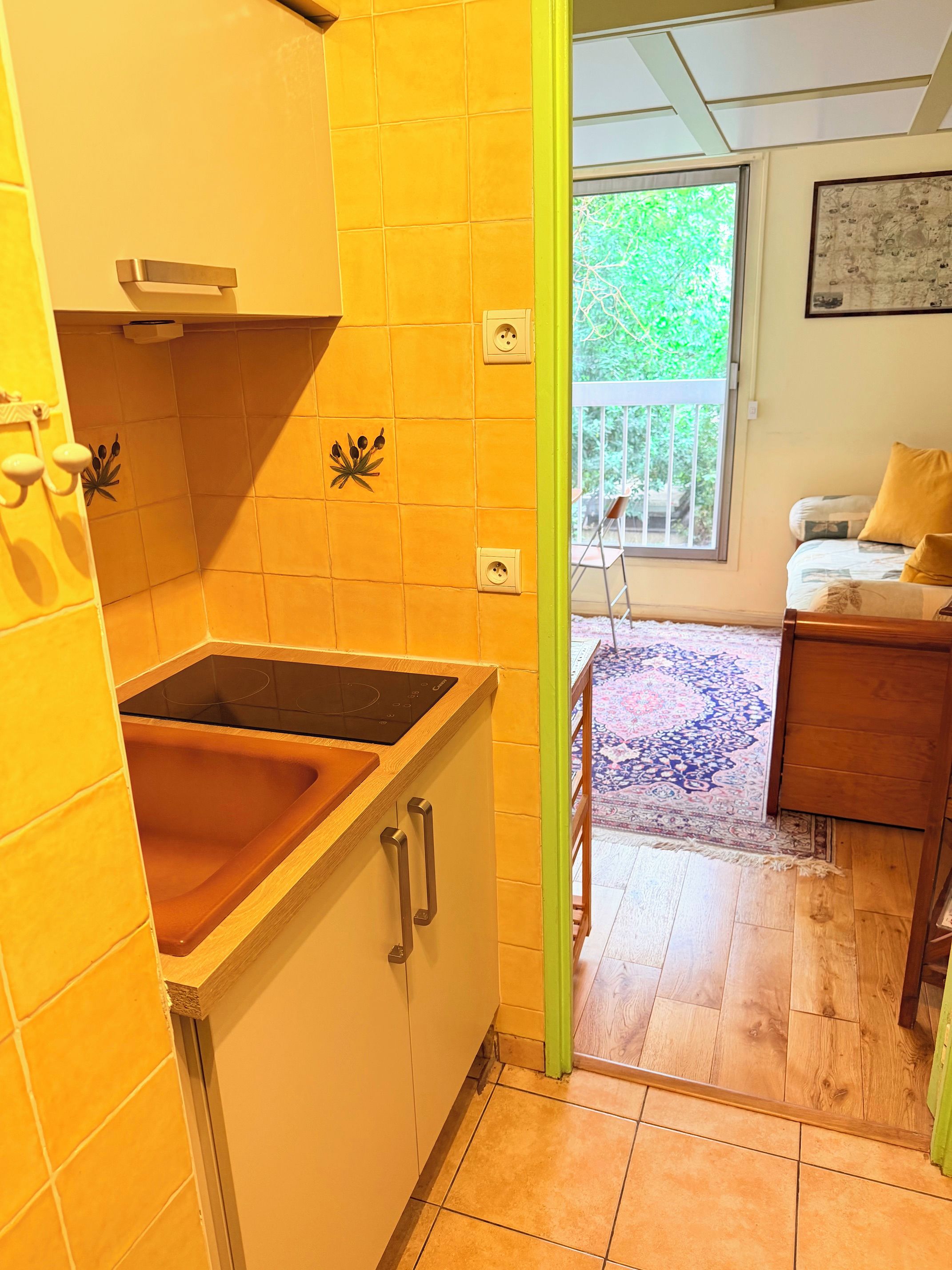 Een keuken met een ingebouwde kookplaat, een spoelbak en een kast met een handgreep.