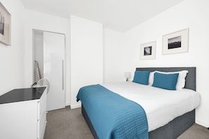 A bedroom with a bed, a desk, a chair, and a door. - Sterling House by City Living  (London)