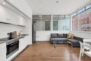A modern kitchen with white cabinets, a built-in oven, and a refrigerator. - Sterling House by City Living  (London)