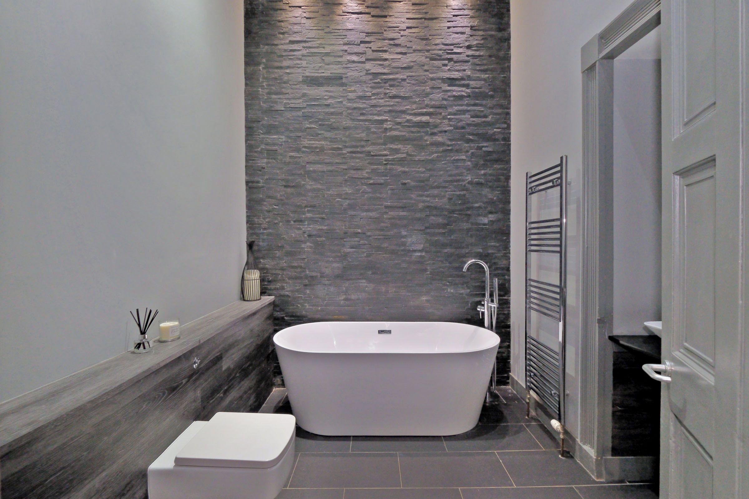 A modern bathroom with a freestanding bathtub, a toilet, and a shower area.