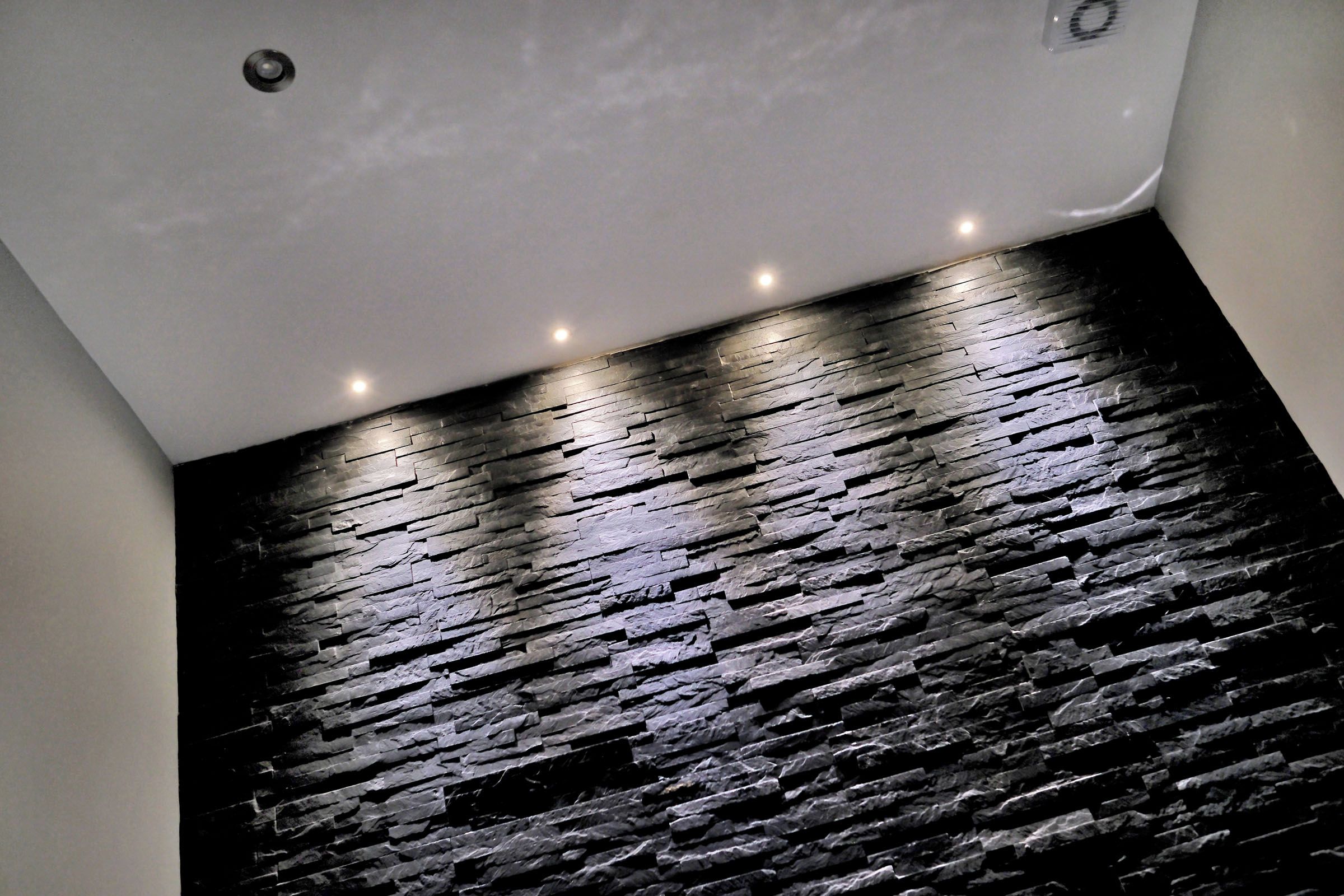 A room with a stone-textured floor and a white ceiling with recessed lighting.