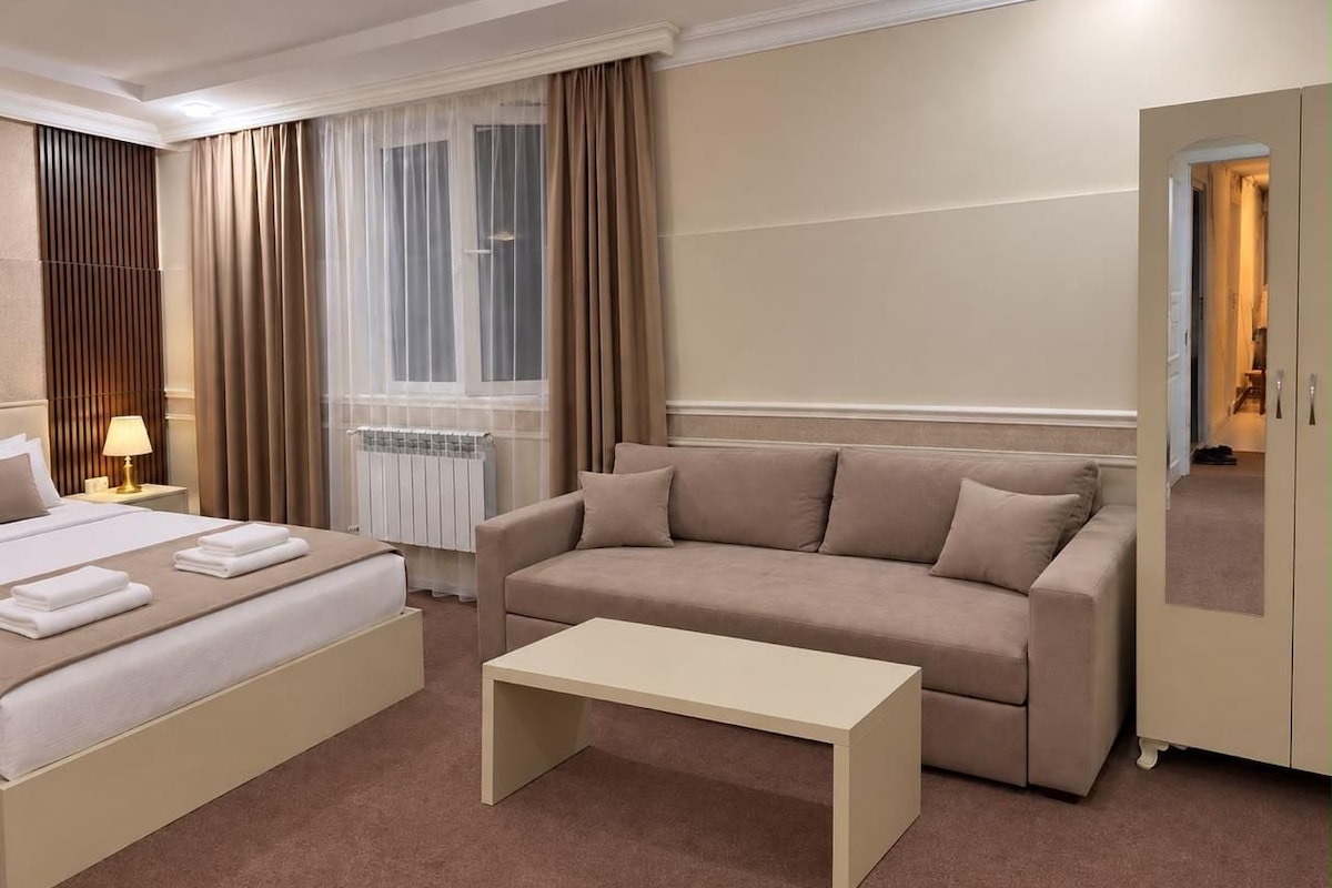 Ein Hotelzimmer mit Bett, einer Couch, einem Couchtisch und einem Kleiderschrank.
