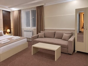 Ein Hotelzimmer mit Bett, einer Couch, einem Couchtisch und einem Kleiderschrank.