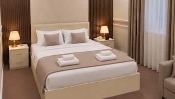A hotel room with a large bed, two bedside tables, a chair, and a window with curtains.