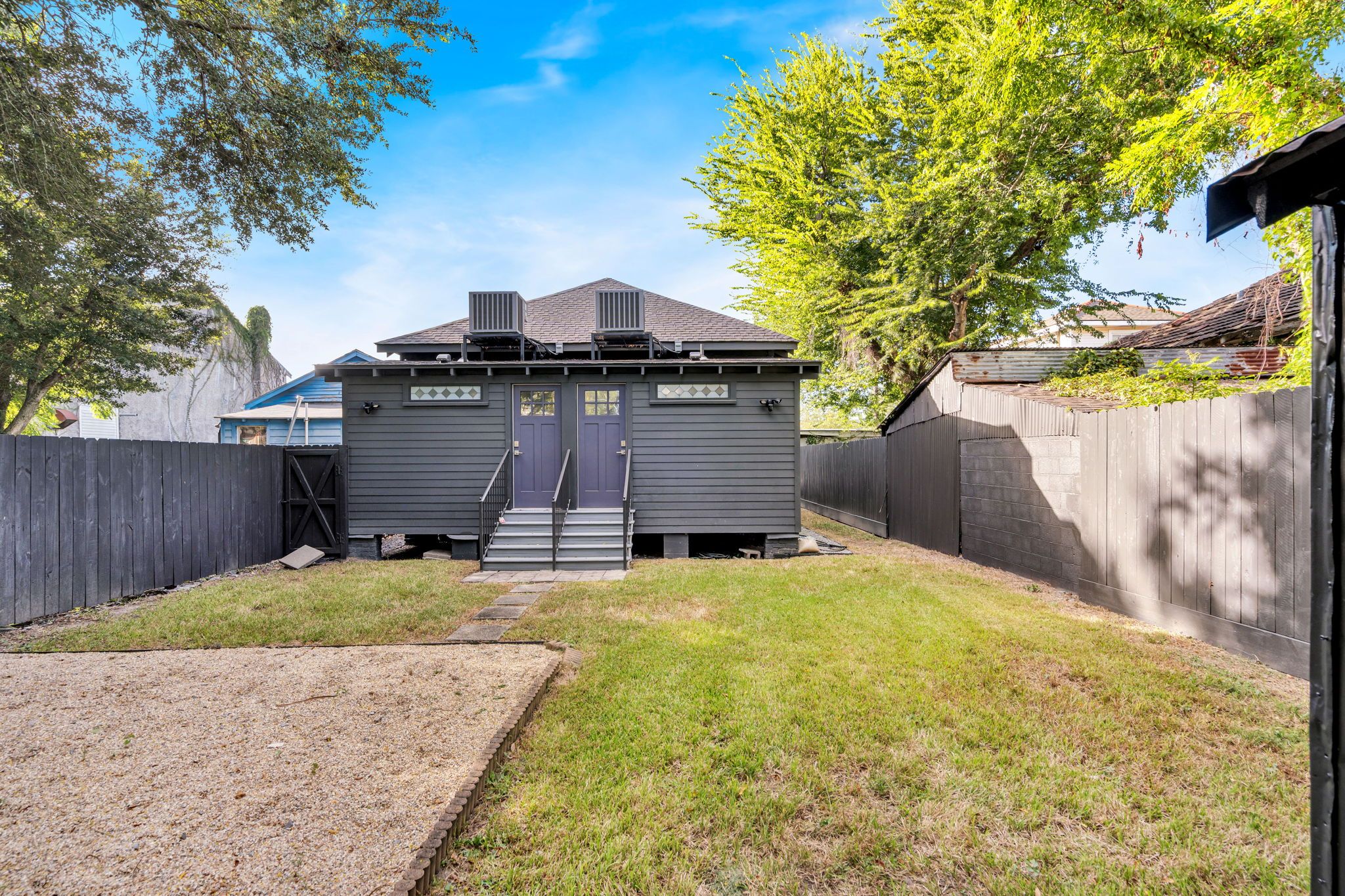 A fenced backyard with a small shed, a gravel path, and a grassy area.