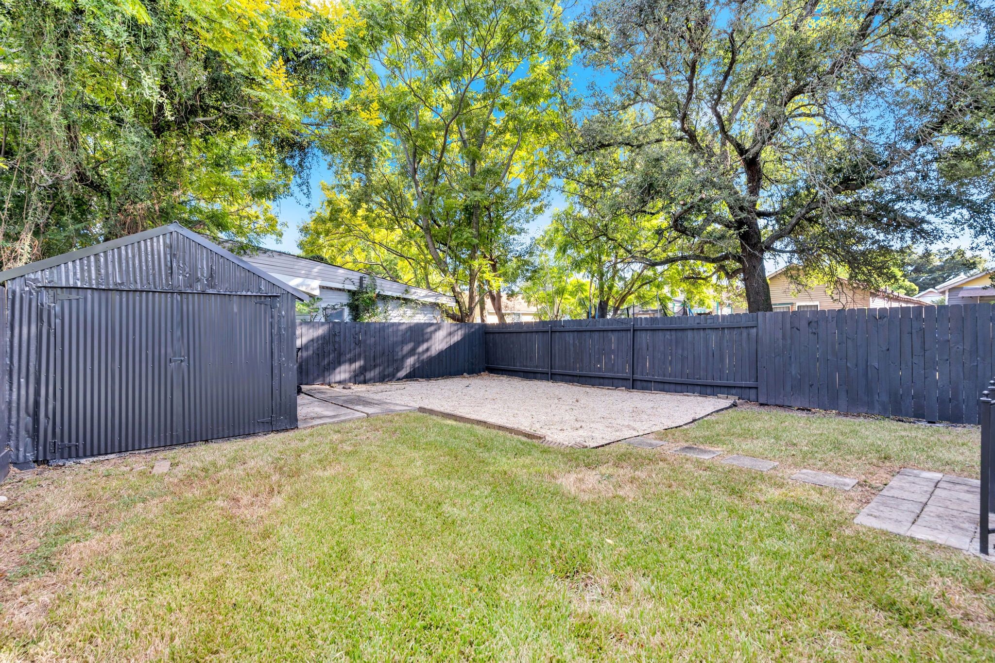 A backyard with a fenced area, a shed, and a grassy lawn.
