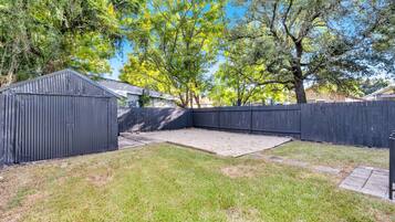 A backyard with a fenced area, a shed, and a grassy lawn.