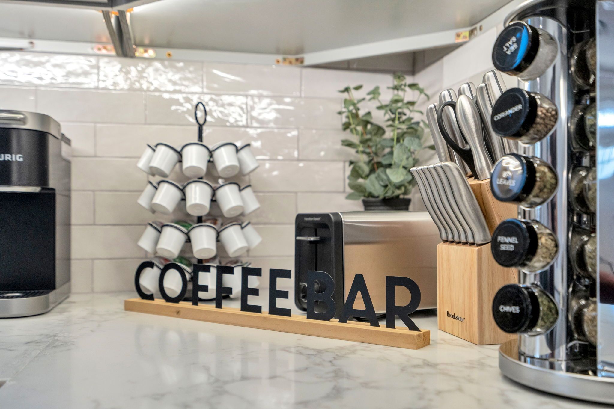 A kitchen counter with a coffee bar setup, including a coffee machine, a grinder, and a set of knives.