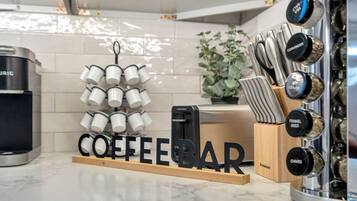 A kitchen counter with a coffee bar setup, including a coffee machine, a grinder, and a set of knives.