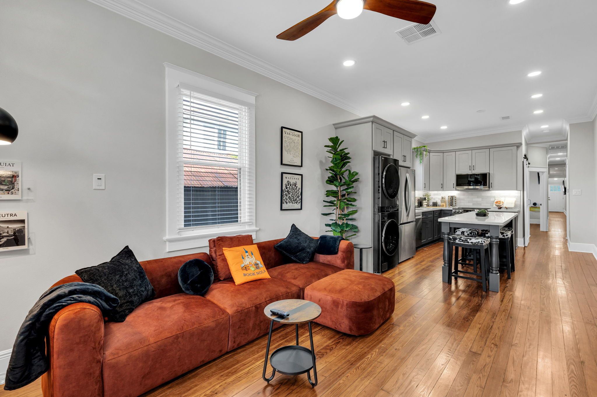 A modern living room with a sectional sofa, a small side table, and a ceiling fan.