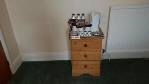 Un mueble de madera con un cartel de 'No Fumar', que contiene varias botellas y una cafetera.