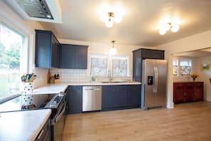 Una cocina moderna con lavavajillas, refrigerador y ventana con cortina floral.