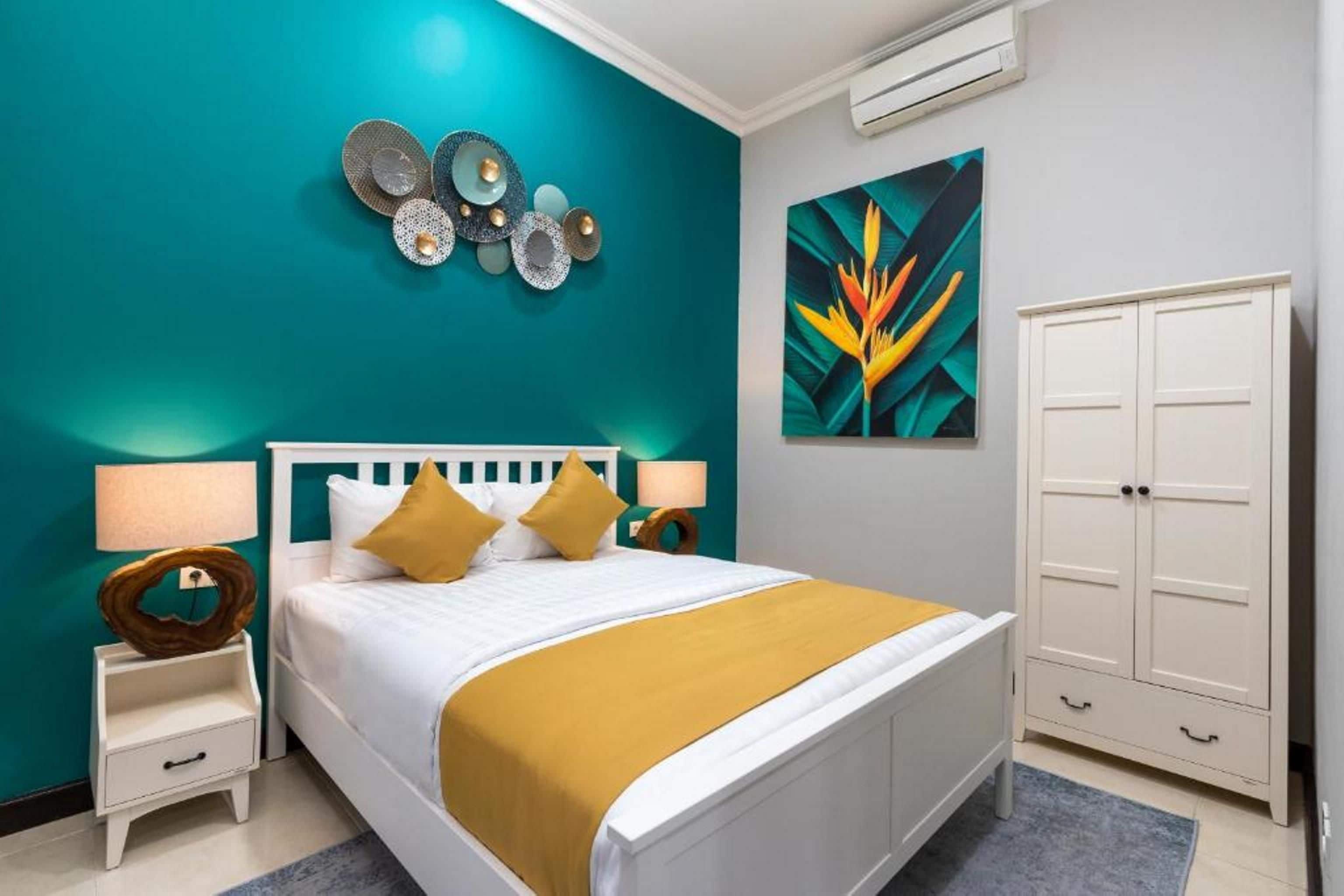 Une chambre à coucher comprenant un lit, des tables de chevet, une armoire et un mur décoré d’assiettes et d’un tableau.
