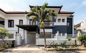Ein zweigeschossiges Haus mit einem verschlossenen Eingang, einer überdachten Veranda und einer Palme im Vorgarten.