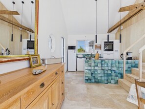 A modern kitchen with wooden cabinetry, a central island with a blue tiled backsplash, and a staircase leading to an upper level. - By the ocean, 9 guests, garden included (La Guérinière)