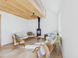 A cozy living room with wicker furniture, a fireplace, and a large window. - By the ocean, 9 guests, garden included (La Guérinière)