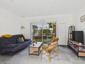 Un salon moderne avec un canapé, une table basse et des fauteuils en osier.