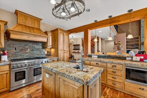 A kitchen with a central island, built-in oven, and a stone backsplash. - West Cobb- Private- sleeps 16- hot tub- petsOK (McCall)