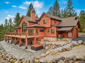 A two-story wooden cabin with a balcony, stone pathway, and a stone wall surrounding the property. - West Cobb- Private- sleeps 16- hot tub- petsOK (McCall)