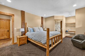 Ein Schlafzimmer mit einem hölzernen Bett, einem Nachttisch, einem Sessel und einem Spiegel.