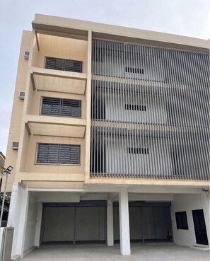 A multi-story building with a flat facade, large windows, and a covered entrance area.