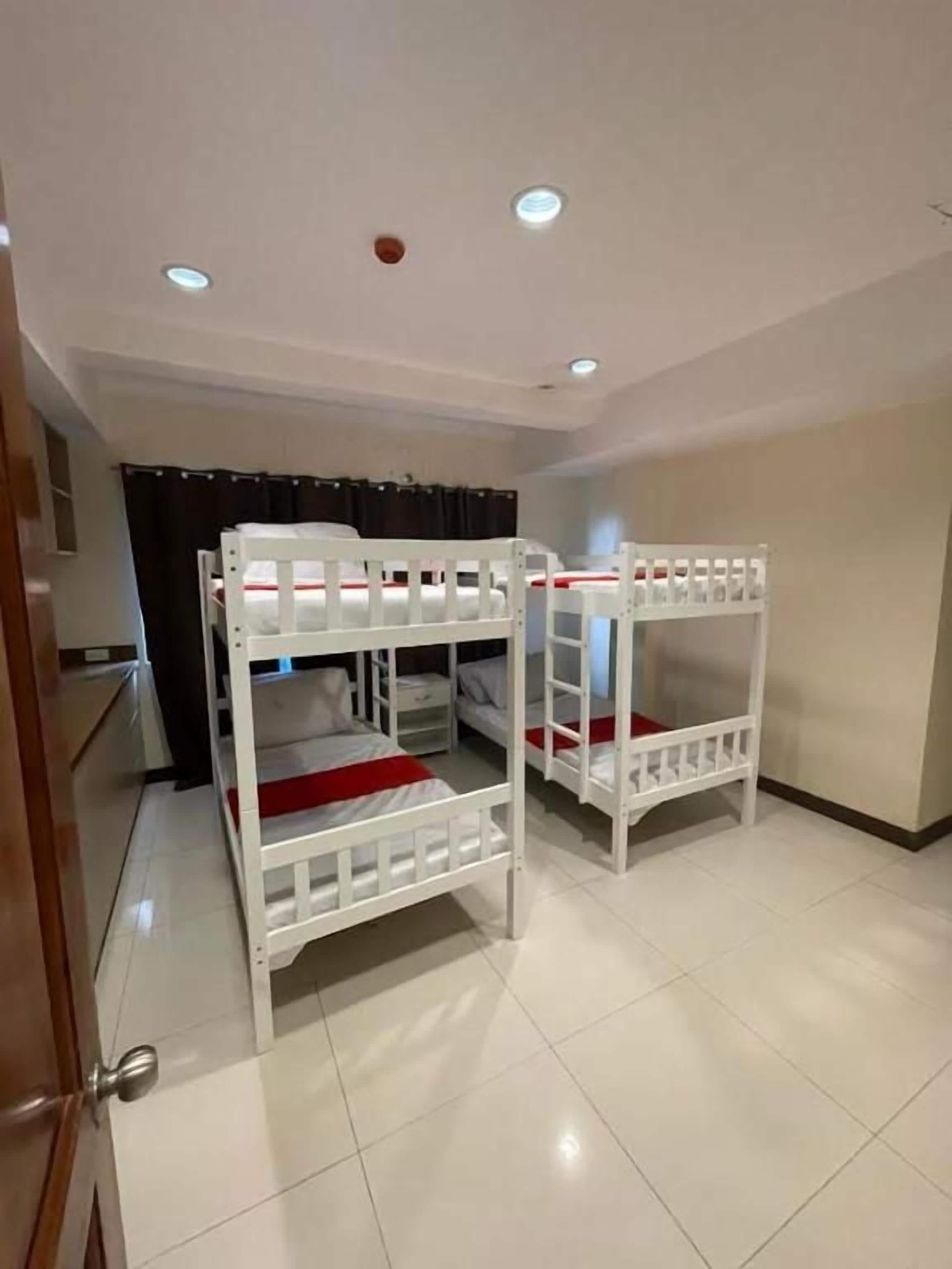Una habitación con literas, una puerta e iluminación empotrada en el techo.