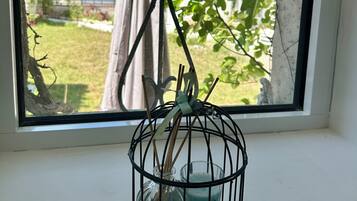 Ein Fenster mit einem Vogelkäfig aus Metall, der eine Kerze und eine Glasflasche enthält.