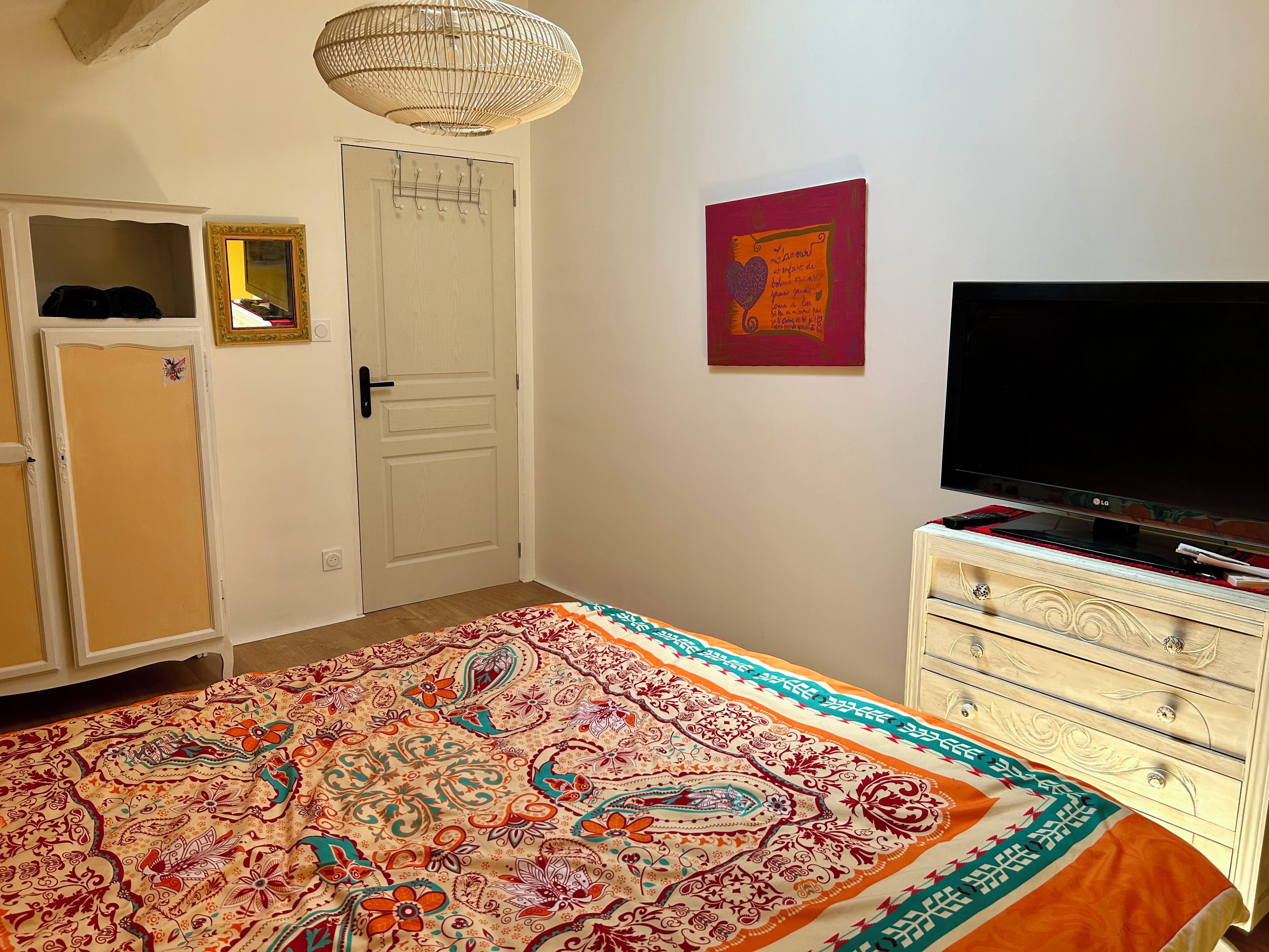 Une chambre à coucher avec un lit, une télévision, une armoire et une porte.