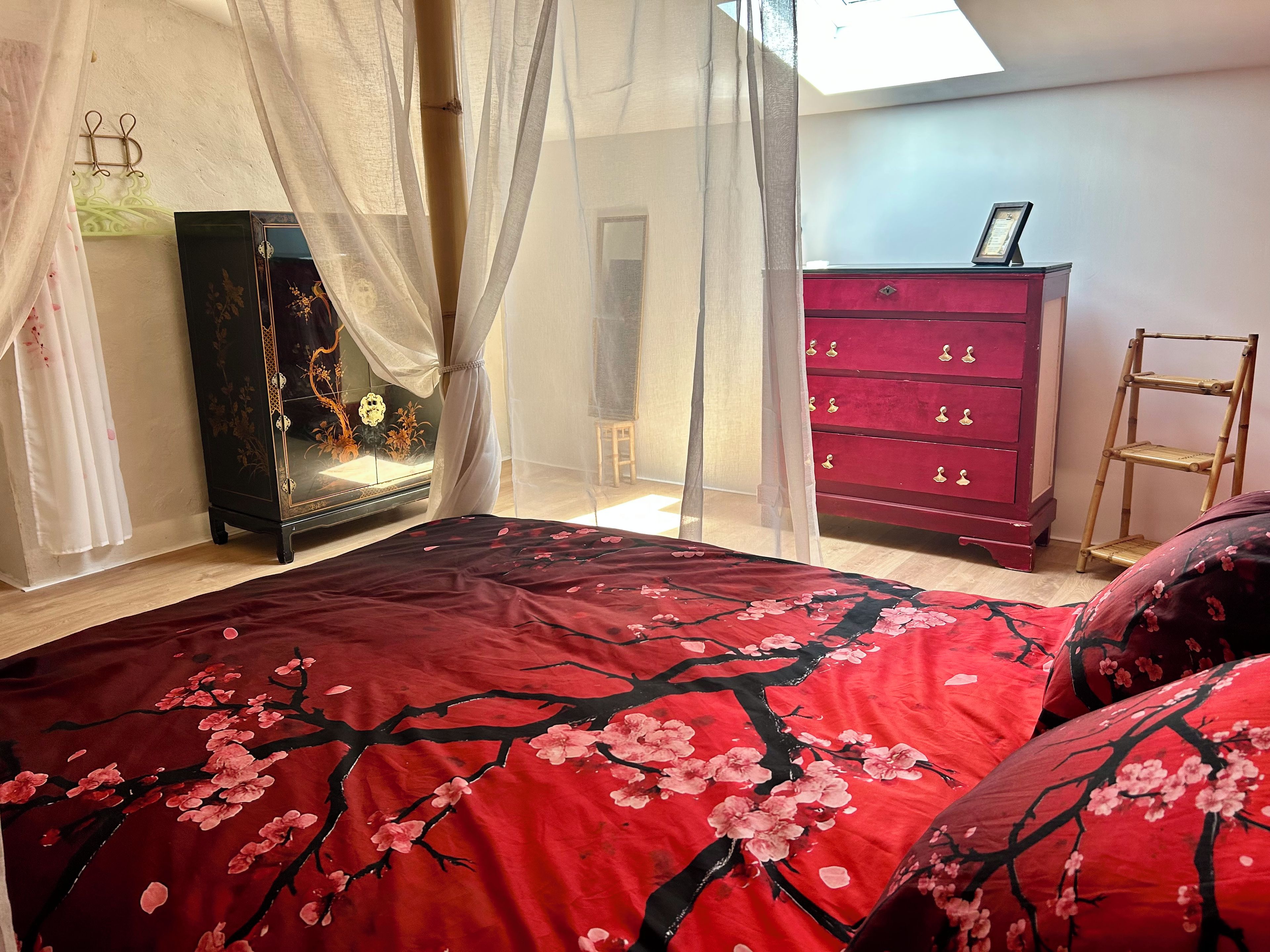 Una camera da letto con un letto, una cassettiera rossa, un tavolino e un mobile decorativo.