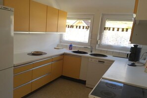 A kitchen with a dishwasher, a stove, and a window with blinds. - Holiday apartment with 1 bedroom (Freudenstadt)